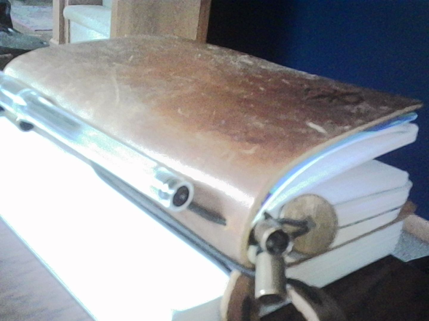 A notebook and pen resting on top of a pad of paper that lives on the desk.