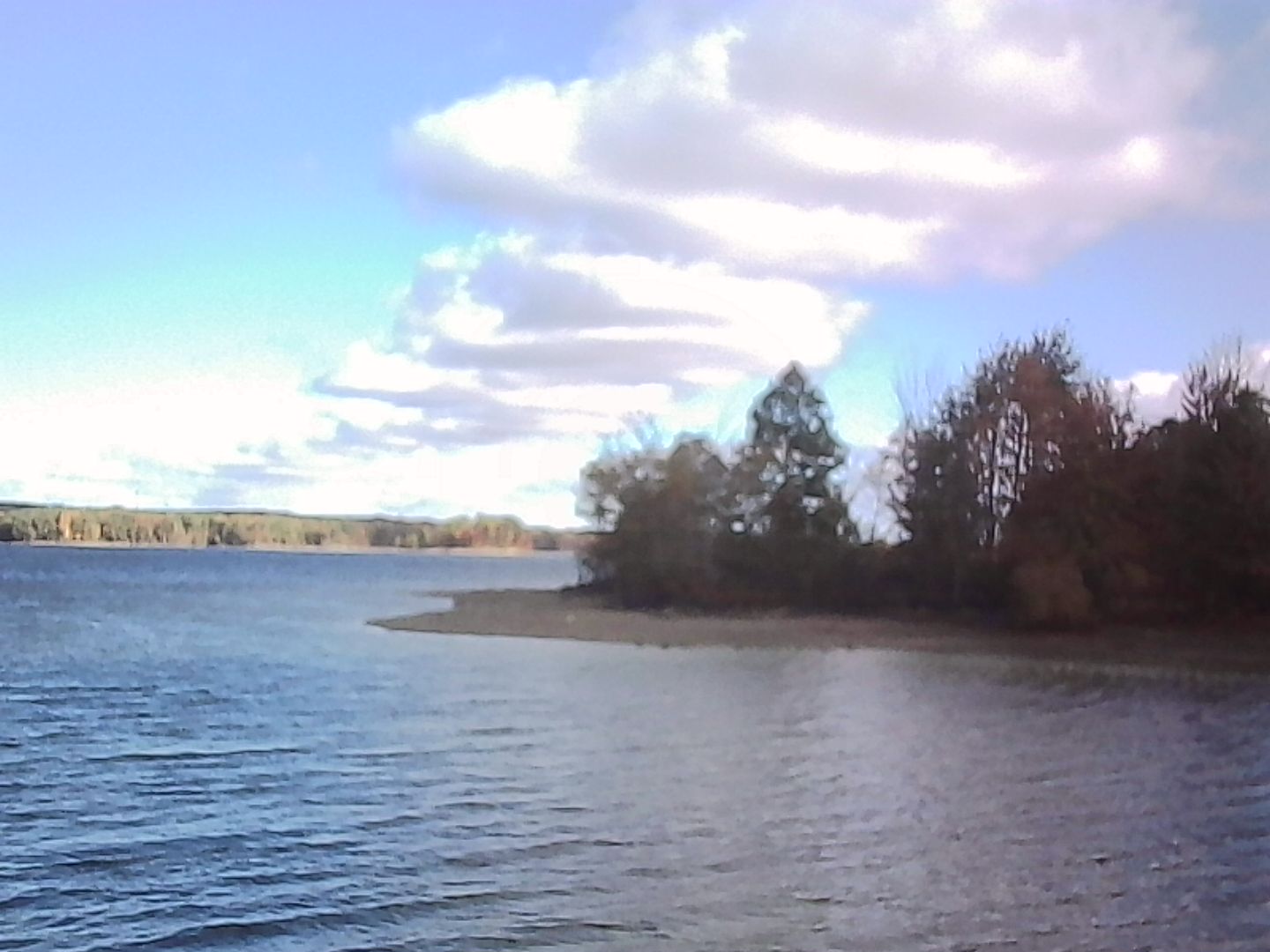 The reservoir and a bit of the land under a blue sky and dramatic clouds.