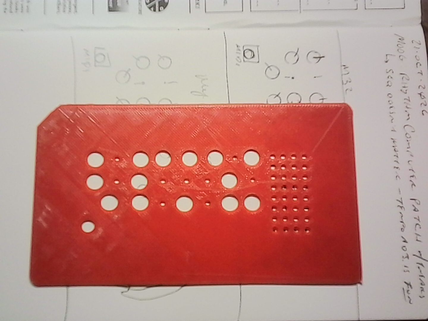 A red template with different sized holes in it that mimic the front panel of the Moog Mother-32 modular synthesizer.